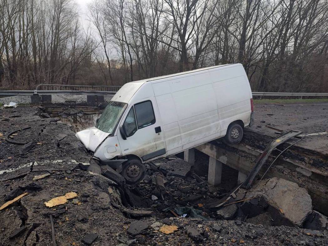 Ein zerstörter weißer Transporter liegt am Straßenrand